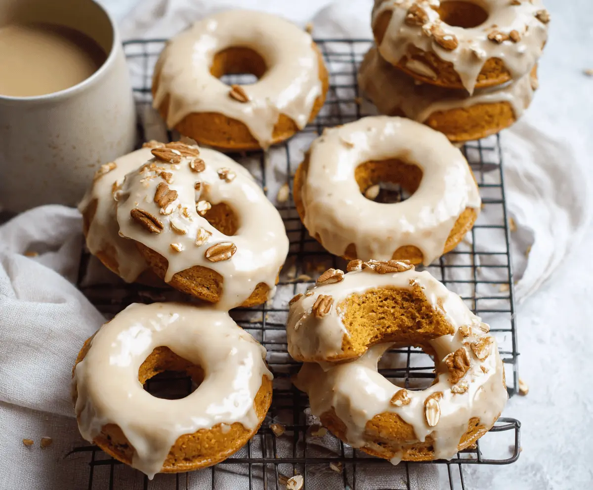 Delicious pumpkin baked donuts topped with shiny maple glaze and a sprinkle of cinnamon, perfect for fall indulgence.