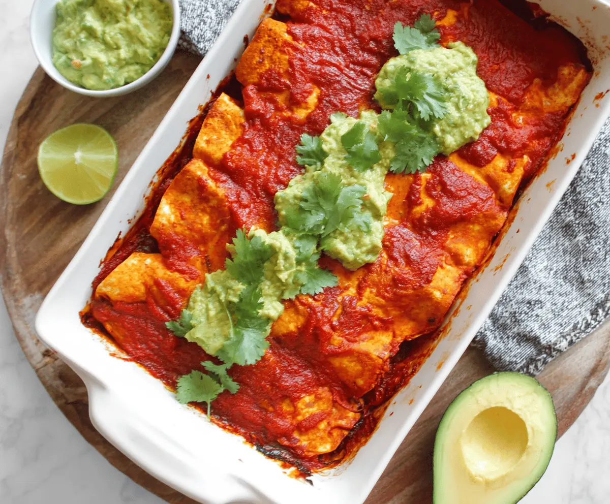 Delicious sweet potato and chickpea enchiladas topped with melted cheese and fresh cilantro on a vibrant plate