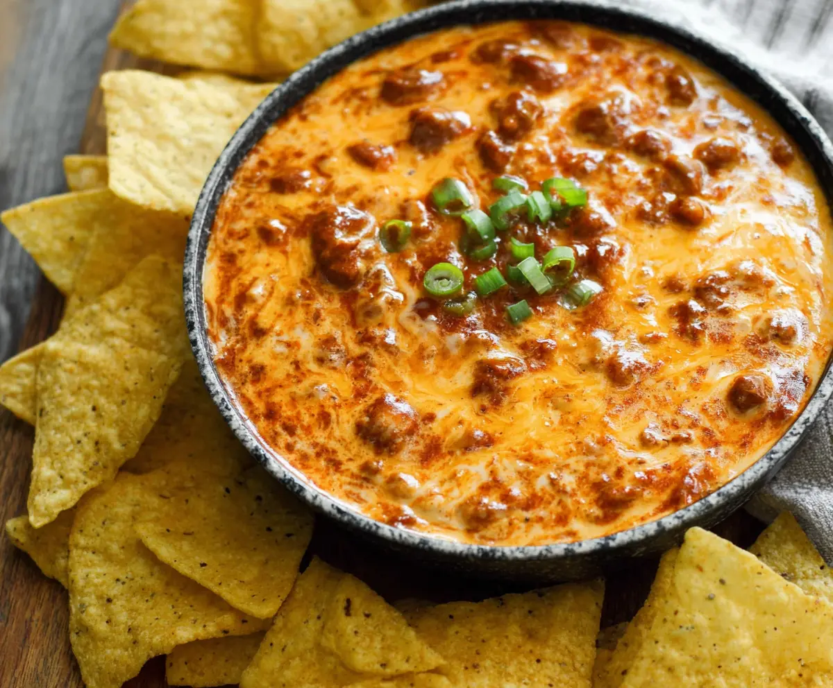 Creamy chili cheese dip served with tortilla chips, perfect for parties and game day snacks.