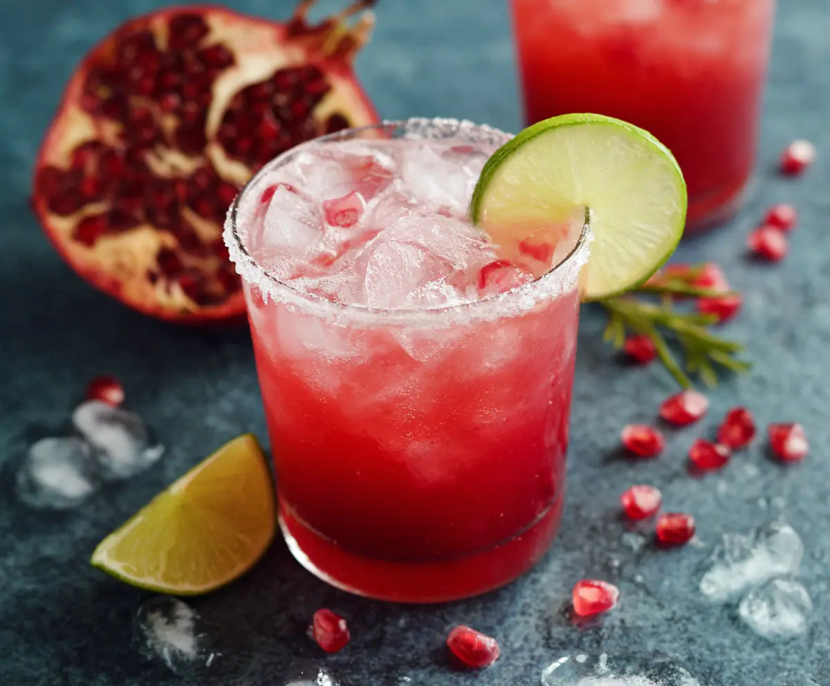 Refreshing Pomegranate Paloma cocktail garnished with fresh lime and pomegranate seeds in a stylish glass.