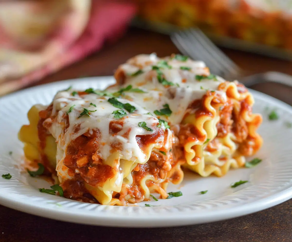 Delicious homemade lasagna roll-ups with rich cheese and meat filling served on a plate.