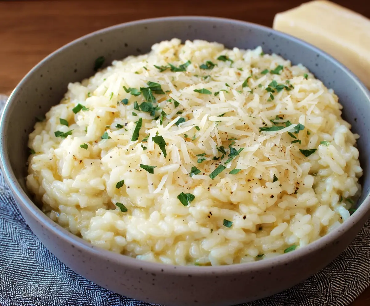 Creamy Parmesan Risotto served in a bowl, garnished with fresh herbs and grated cheese.