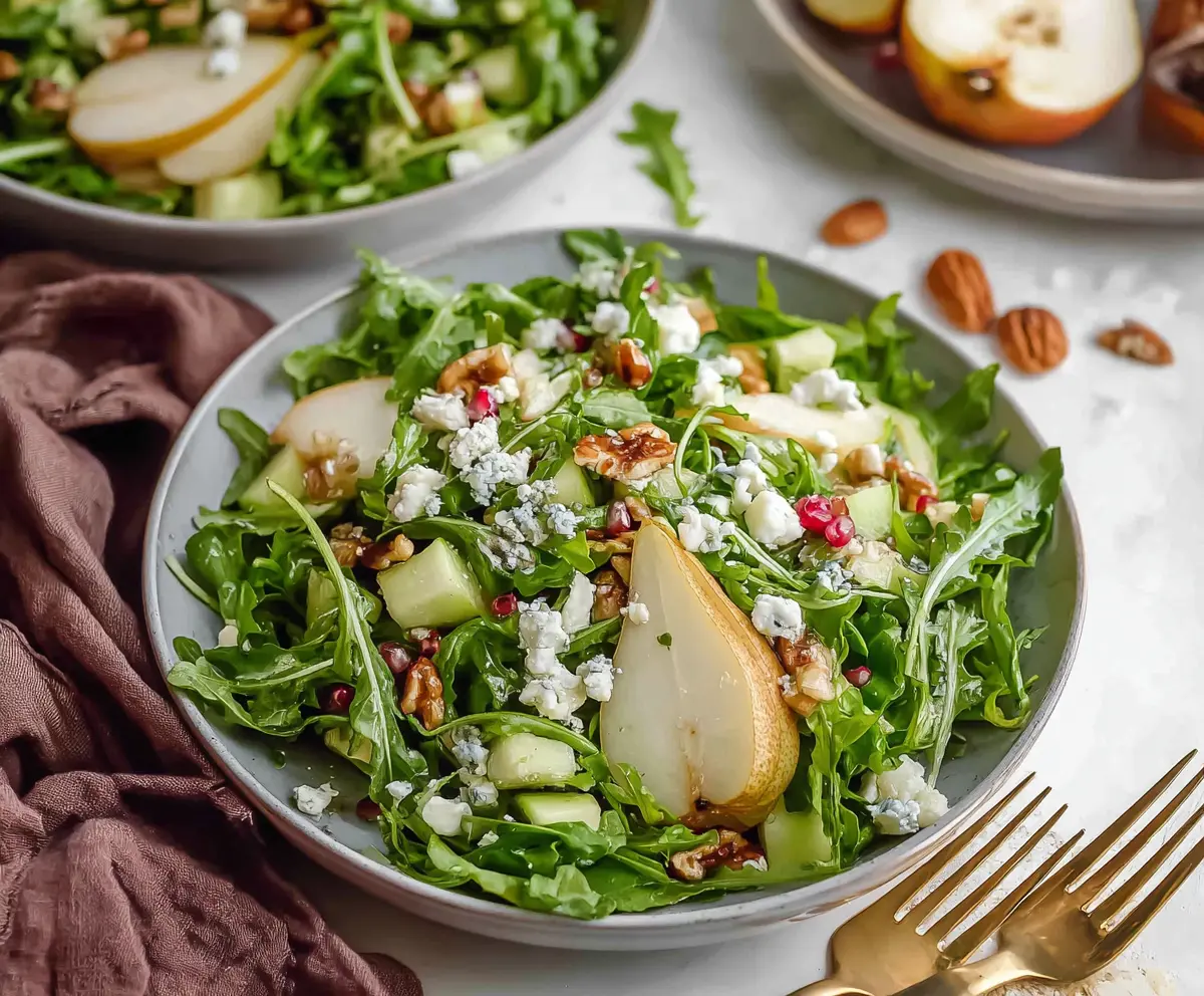 Fresh arugula and ripe pear salad with walnuts and feta cheese in a vibrant, healthy dish.