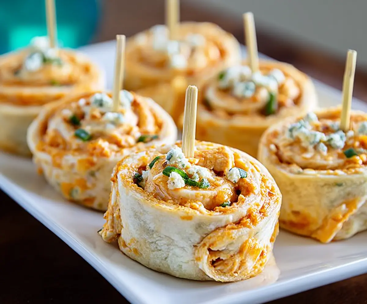 Buffalo chicken pinwheels with crispy edges and creamy filling served on a white plate