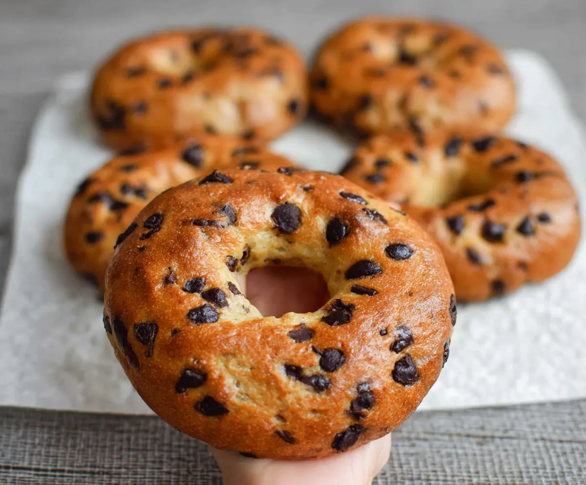 Delicious homemade chocolate chip bagels with melty chocolate chunks topped with a sprinkle of cinnamon.