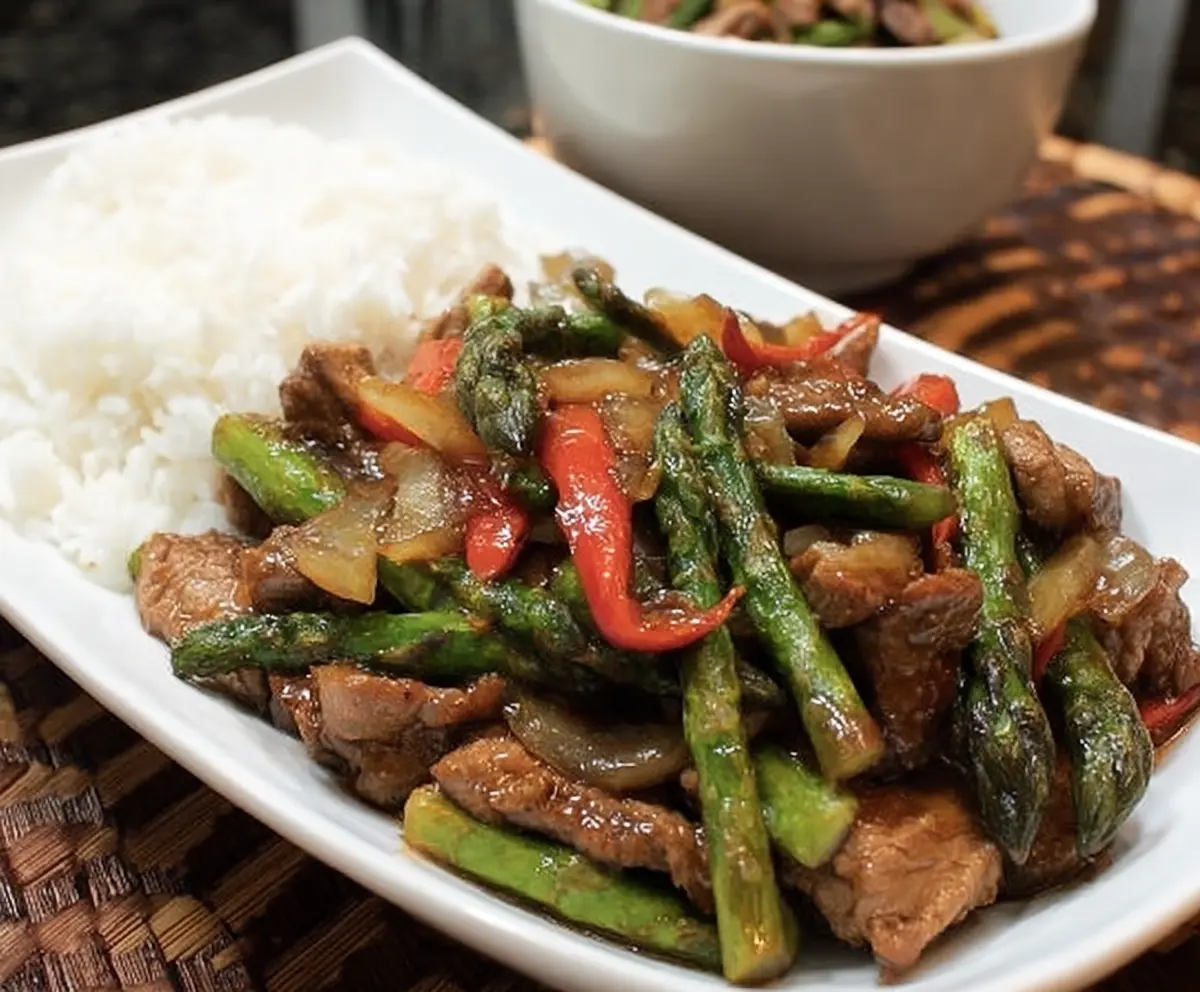 Delicious pork and asparagus stir fry served in a bowl, showcasing fresh ingredients and vibrant colors.