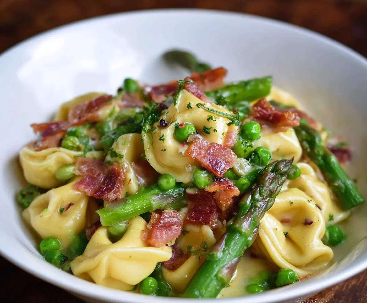 Delicious tortellini pasta with peas, asparagus, and crispy bacon on a plate.