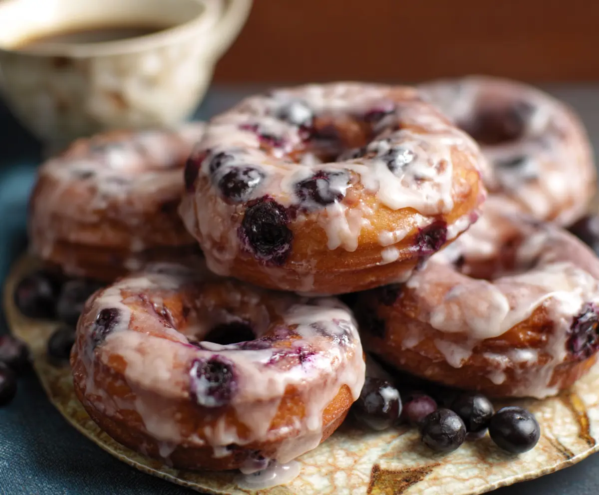 Delicious homemade blueberry cake donuts topped with fresh blueberries and powdered sugar.